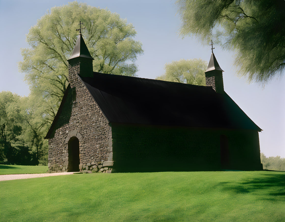 Stone Chapel with Twin Spires Surrounded by Trees under Clear Sky