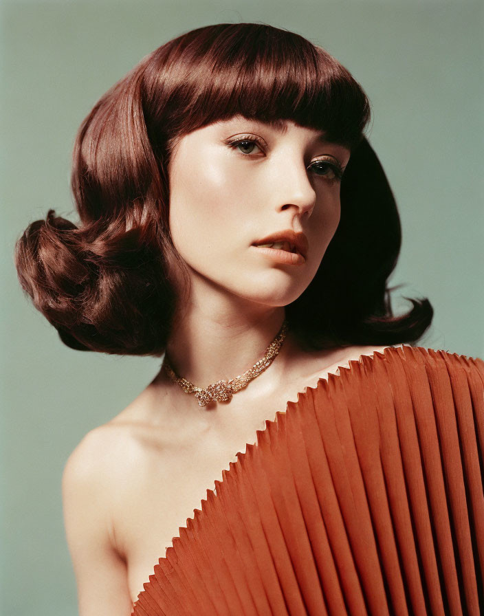 Bob Haircut Woman in Orange Pleated Dress with Necklace