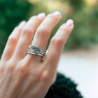 Close-up of hand with stacked rings: silver band & turquoise gemstone on blurred green background