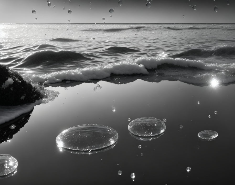 Serene monochrome beach scene with gentle waves and suspended water droplets capturing sunlight reflections