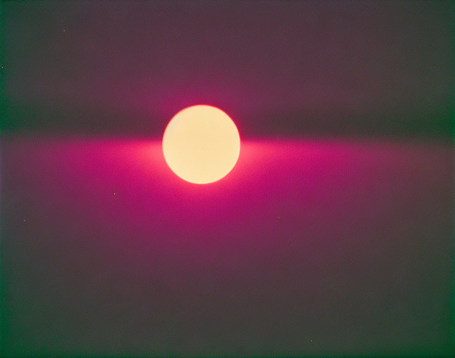 Colorful round light with pink and purple halo on dark background