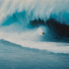 Surfer riding large blue wave with person floating below