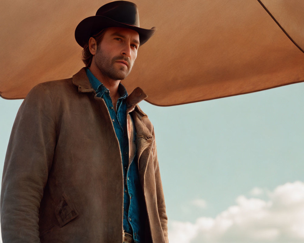 Man in Cowboy Hat and Rugged Jacket Under Wide Sky