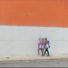 Police officers walking by white building with large orange overhang.