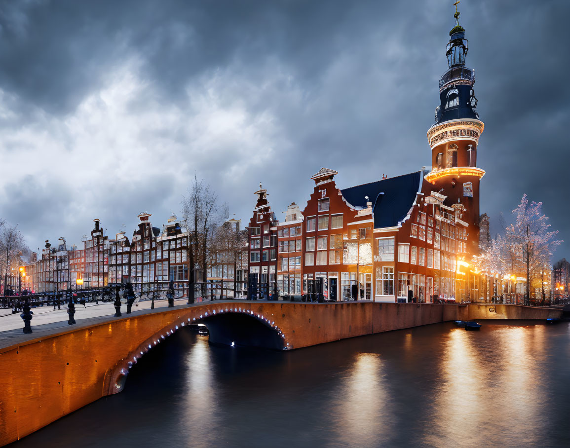 Canal in Amsterdam with illuminated bridge and historical buildings at night