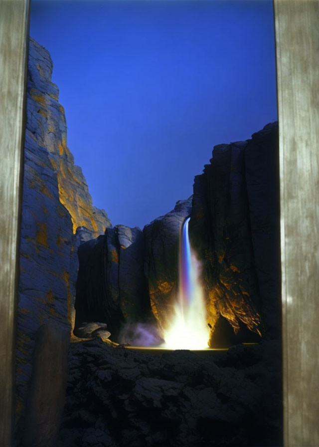 Rainbow waterfall between dark rocks under dusky blue sky