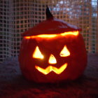 Cat-eared jack-o'-lantern by rain-splattered window emits eerie glow