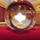 Ornate reflective orb with gear and filigree designs among crimson roses on golden background