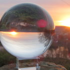 Surreal crystal ball reflecting scenic landscape with mountains, trees, house, sunset, and wildflowers