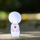 Toddler in White Hoodie with Red Heart, Sitting Outdoors