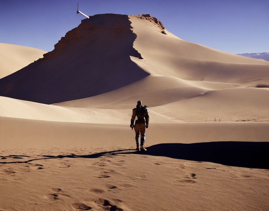 Hiker walking towards tall sand dune in desert landscape