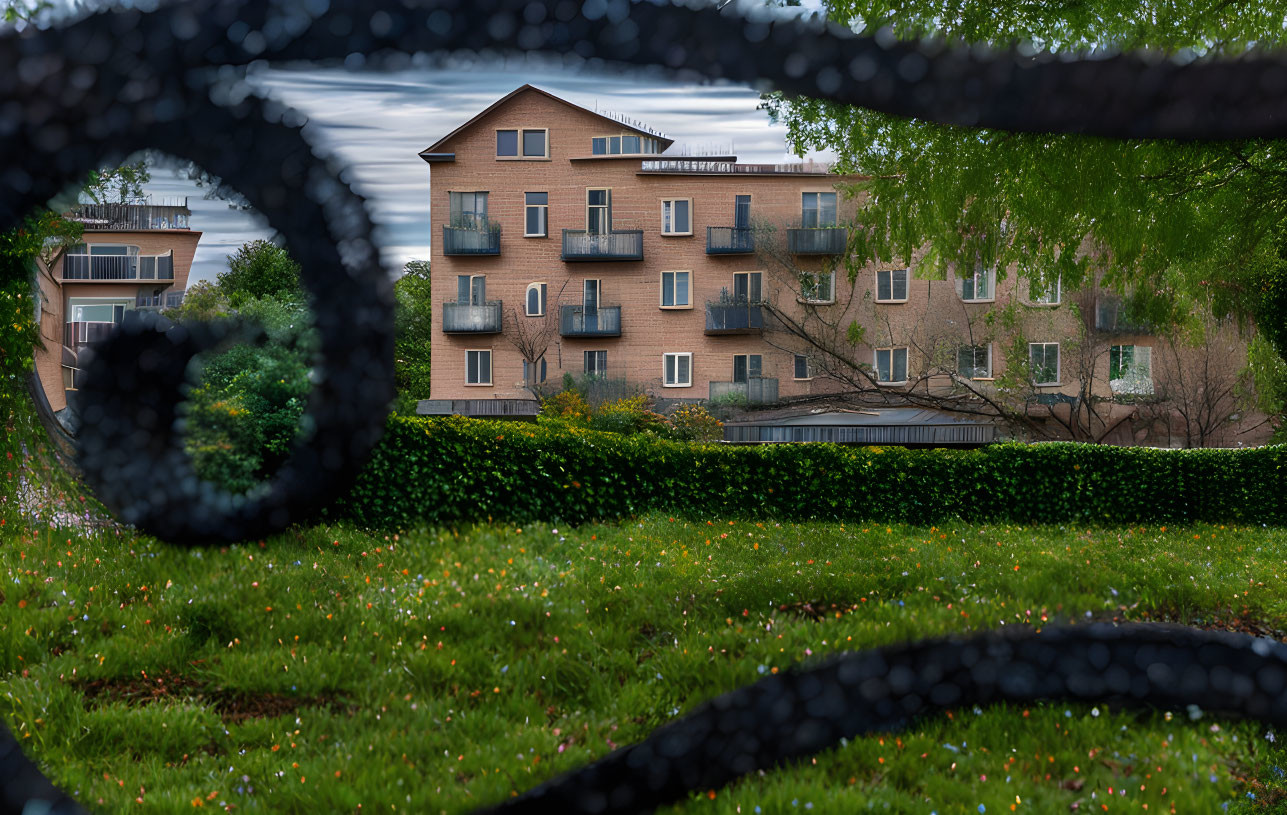 Blurred chain-link fence frames apartment building with balconies