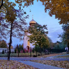 Charming autumn village scene with church, houses, lake, and starry sky