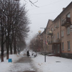 Snow-covered street with stone houses and festive lights in falling snowflakes