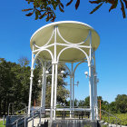 White Gazebo in Sunny Park with Yellow Flowers and Trees