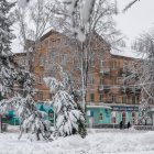 Snow-covered multi-story wooden building in winter landscape