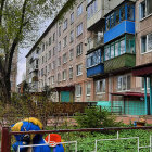 Vibrant apartment building with balconies, lush greenery, and parrots.