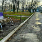 Outdoor scene with bicycle wheel art, stone pathway, benches, greenery, and lighthouse billboard.