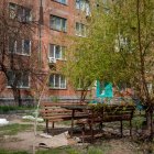 Tranquil garden with wooden bench, lush trees, colorful flowers, and brown building