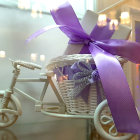 Vintage White Bicycle with Purple Ribbon and Blooming Flowers on Bokeh Light Background