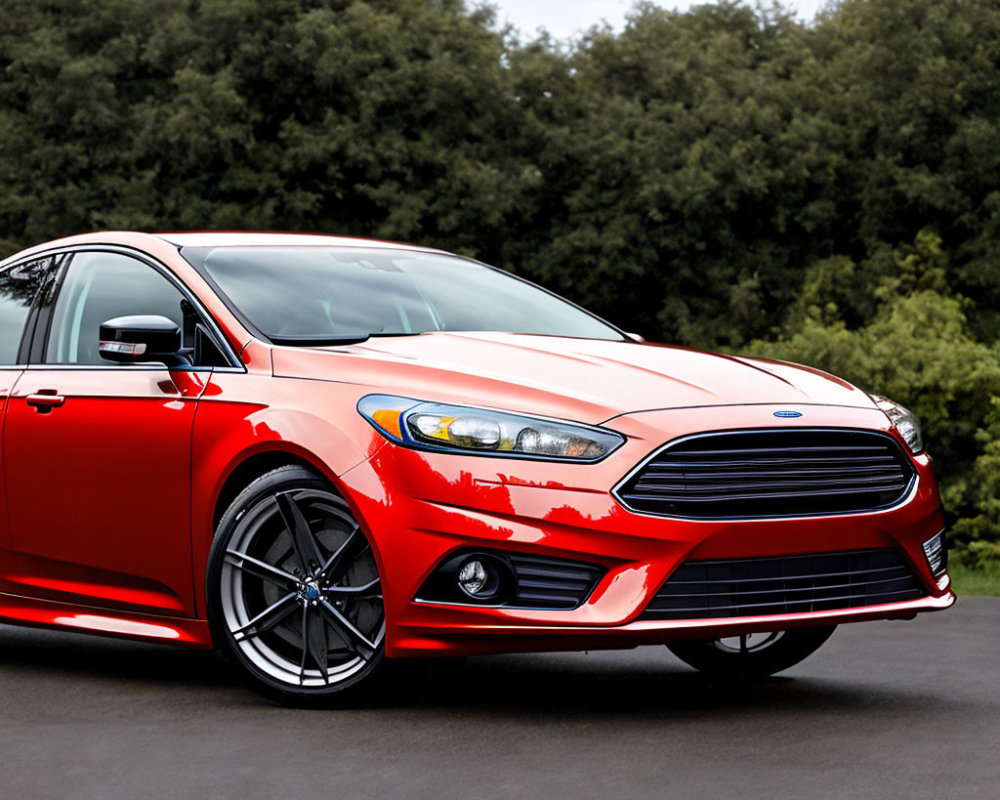 Modern red sedan with alloy wheels parked on green road