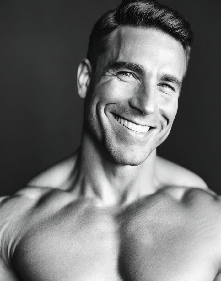 Smiling man in black and white portrait, with short hair and bare shoulders