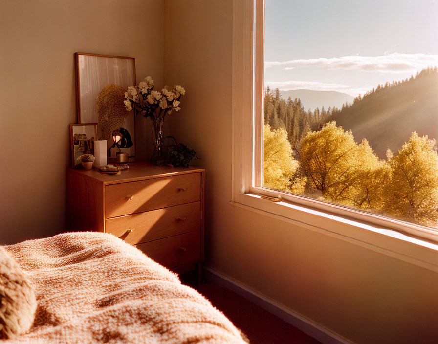 Cozy bedroom with wooden dresser, mirror, flowers, and forest view