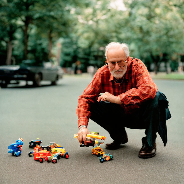 Elderly man arranging toy cars and figure on street