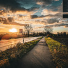 Colorful stylized landscape with setting sun, winding path, quaint houses, yellow flowers, and dynamic