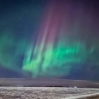 Colorful aurora borealis illuminating snowy landscape at night