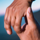 Person's Hand with Well-Manicured Nails Against Blurred Blue Background