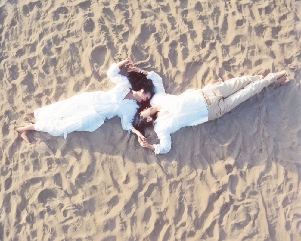 Mirrored image of two individuals lying in sand