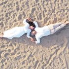 Mirrored image of two individuals lying in sand