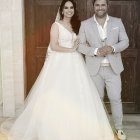 Bride and groom in off-shoulder gown and gray suit against floral backdrop