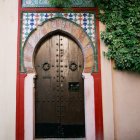 Ornate Archway with Gold and Turquoise Designs in Lush Courtyard