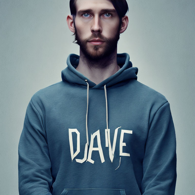 Bearded man with blue eyes in "DAVE" hoodie on grey background