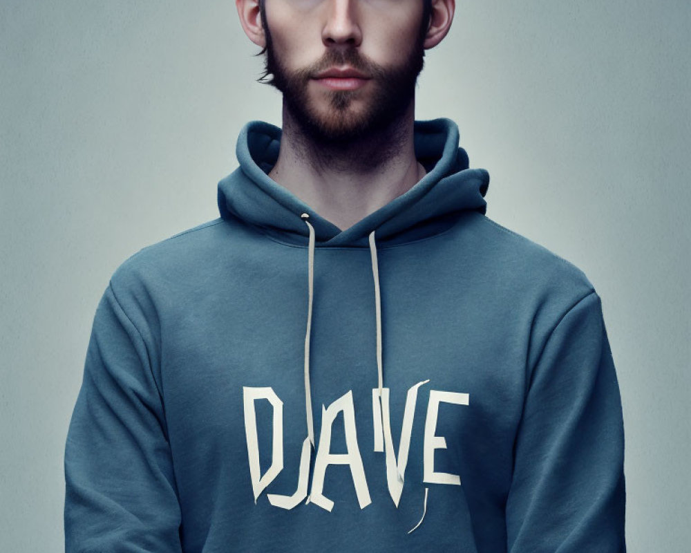 Bearded man with blue eyes in "DAVE" hoodie on grey background