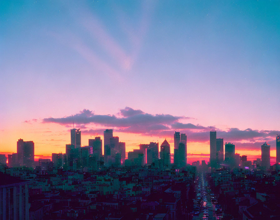 City skyline at dusk with silhouetted skyscrapers against vibrant pink and blue sky