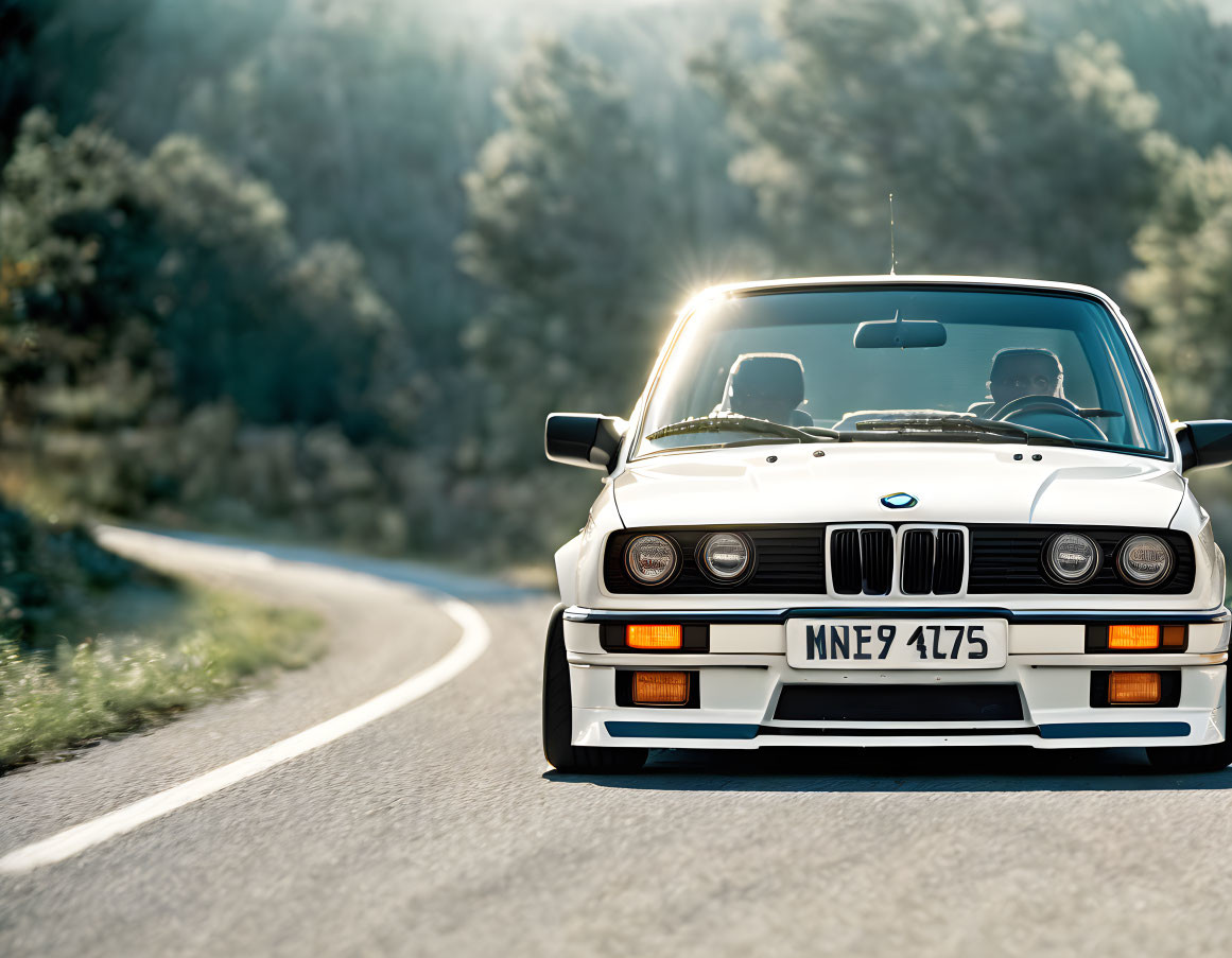 Vintage BMW car with driver and passenger on sunlit road in natural scenery