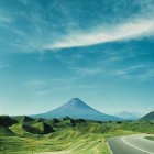 Majestic volcano viewed from winding road through verdant fields