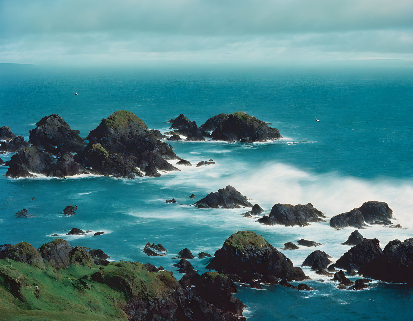 Rocky Islets in Frothy Blue Sea Waves on Rugged Coastline