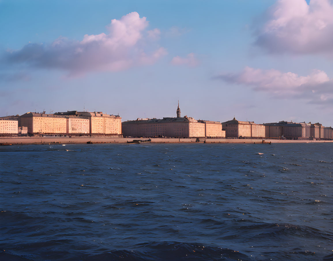 Historic waterfront building complex at sunset by serene river.