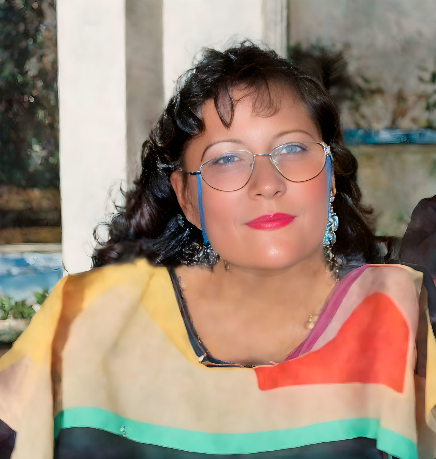 Smiling woman in glasses with colorful attire and earrings