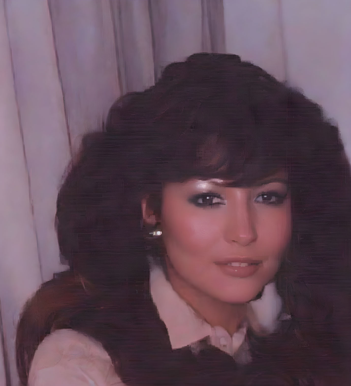 Portrait of woman with voluminous hair and white shirt in front of curtain