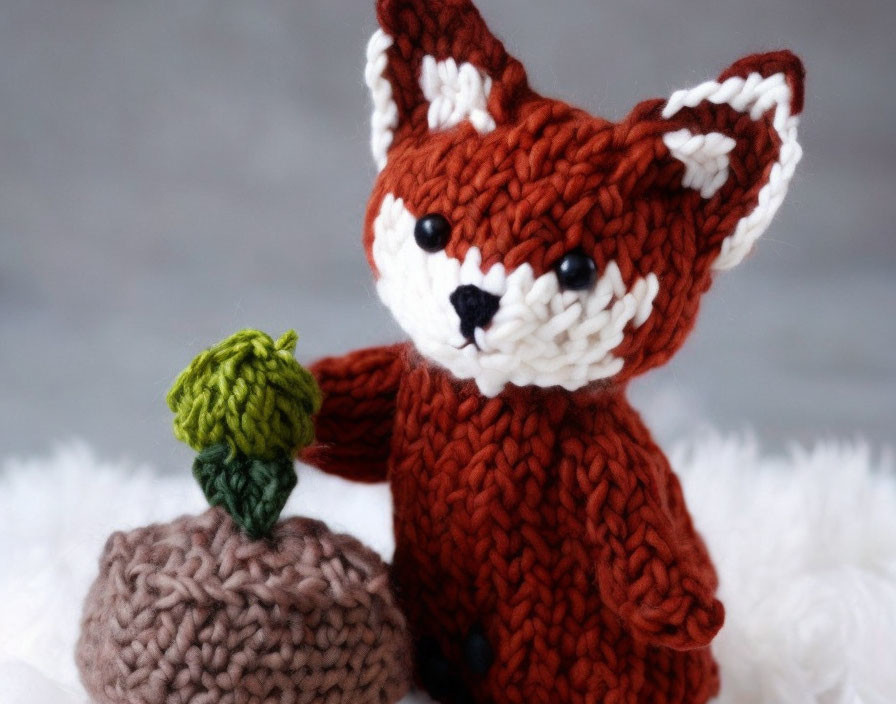 Handmade Knitted Fox Toy with White and Brown Yarn Holding Green Object