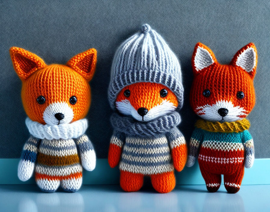 Knitted Toy Foxes in Striped Sweaters on Blue Background
