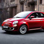 Red Fiat 500 with white roof and chrome wheels on cobblestone street