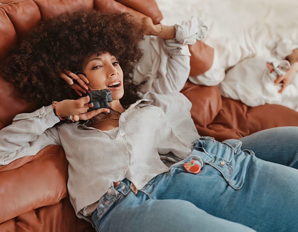 Curly-haired woman on sofa talking on phone in casual attire