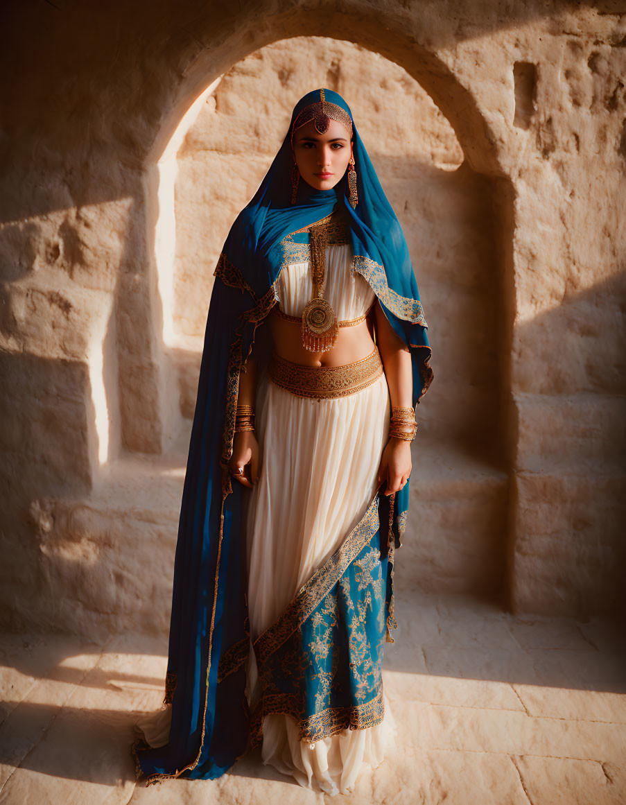 Traditional attire woman in blue headscarf and gold jewelry in stone archway