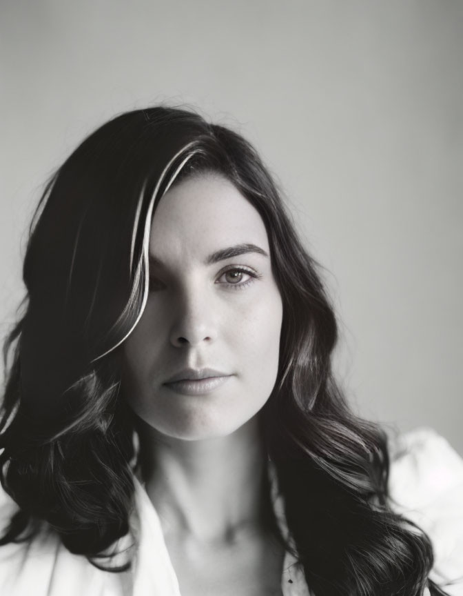 Portrait of woman with dark hair and white blouse in monochrome.